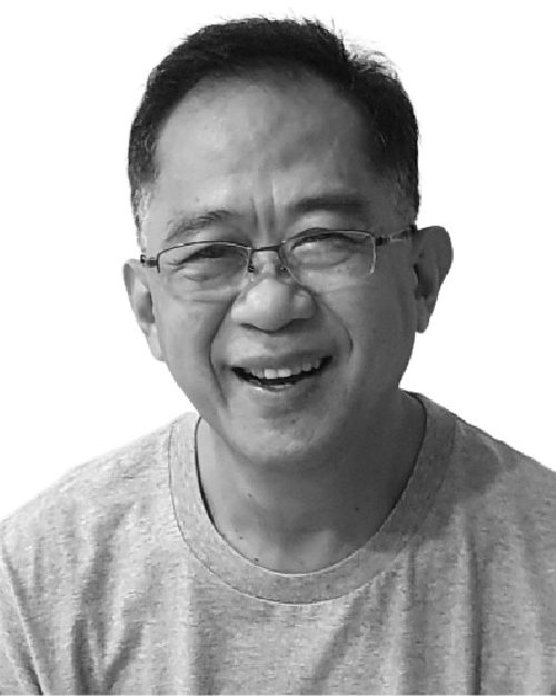 Black and white photo of Mike Chin, he is smiling, has short hair and is wearing a grey t-shirt